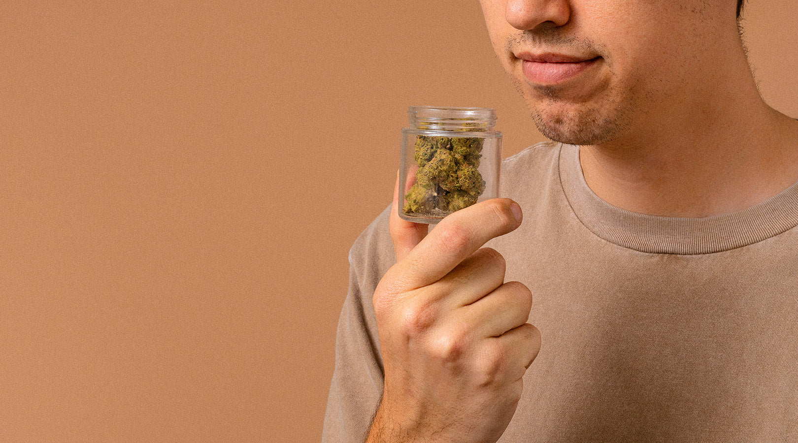 Photo of man smelling weed in jar.
