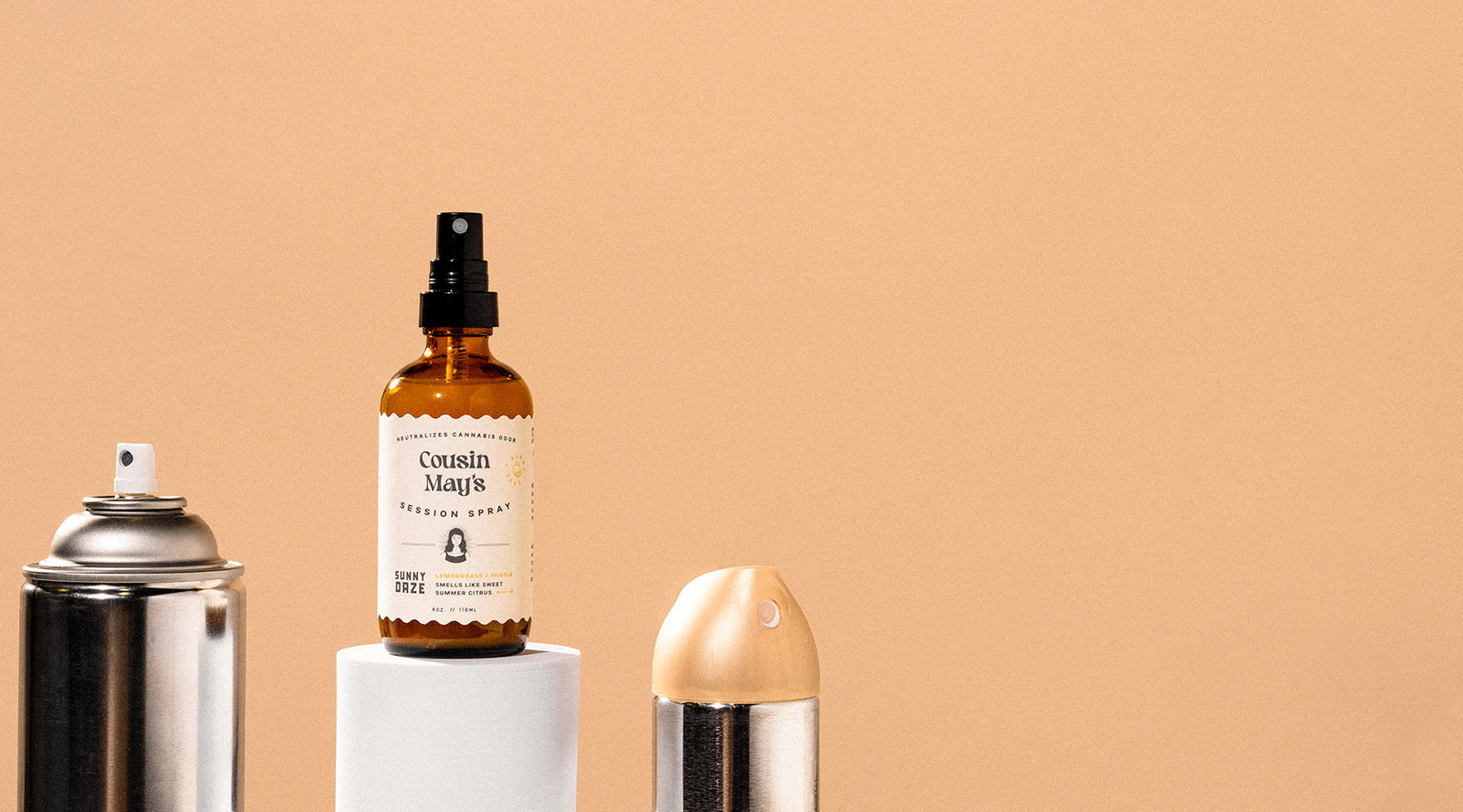 A bottle of Cousin May's stands higher than conventional cans of aerosol air fresheners.