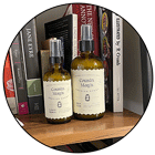 Two bottles of Cousin May's rest on a bookshelf in a customer's home.